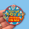 “Embroidered circular patch held in hand featuring a smiling cartoon utensil face above bold lettering, with playful illustrated arms, clouds, and bright blue, red, yellow, and white stitching.”