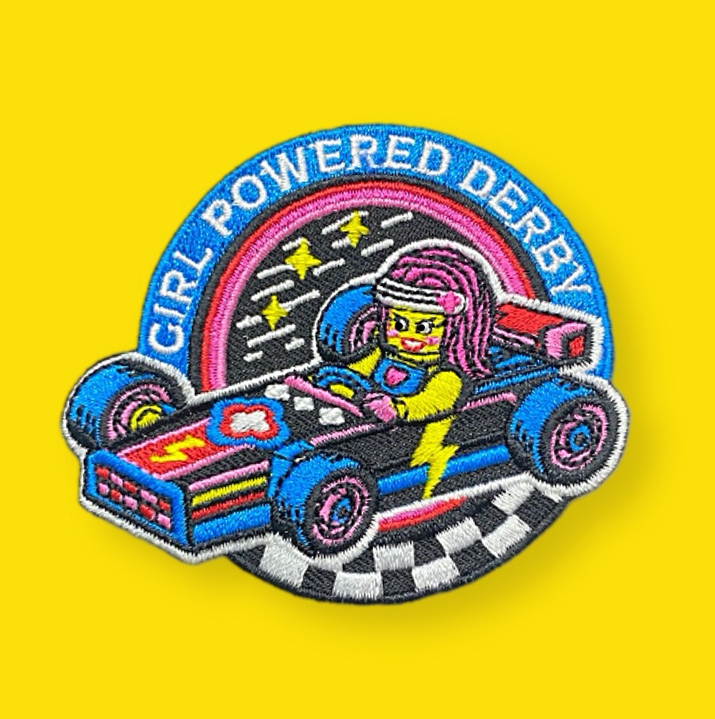 Embroidered patch of a girl in a derby car with 'Girl Powered Derby' text on a yellow background