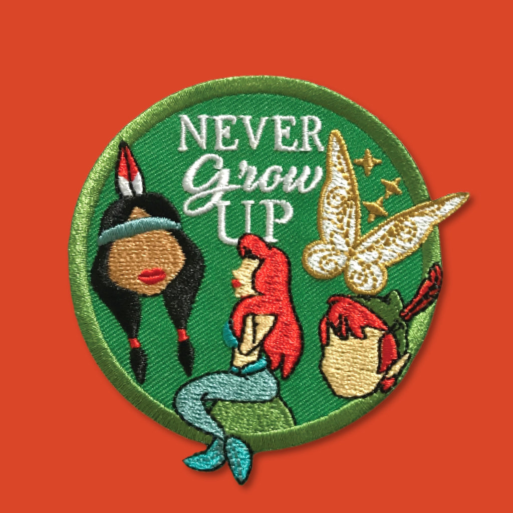 “Embroidered circular patch with a green background featuring a red-haired mermaid seated at center, surrounded by stylized character silhouettes, a golden fairy figure, and white decorative lettering, stitched in green, red, gold, and teal.”
