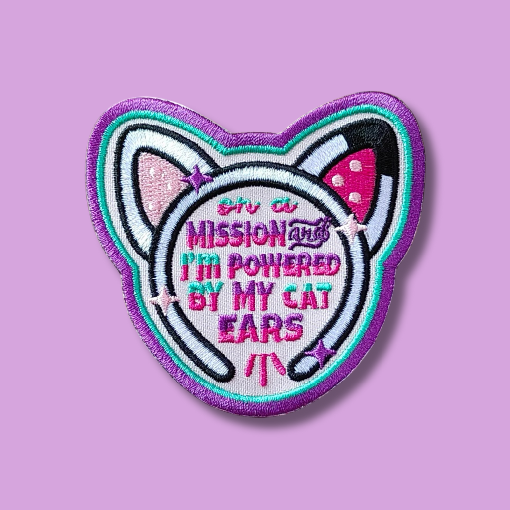 Cat-ear headset embroidered patch with purple border and playful mission-themed phrase